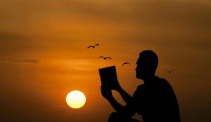 Man reading book at sunset